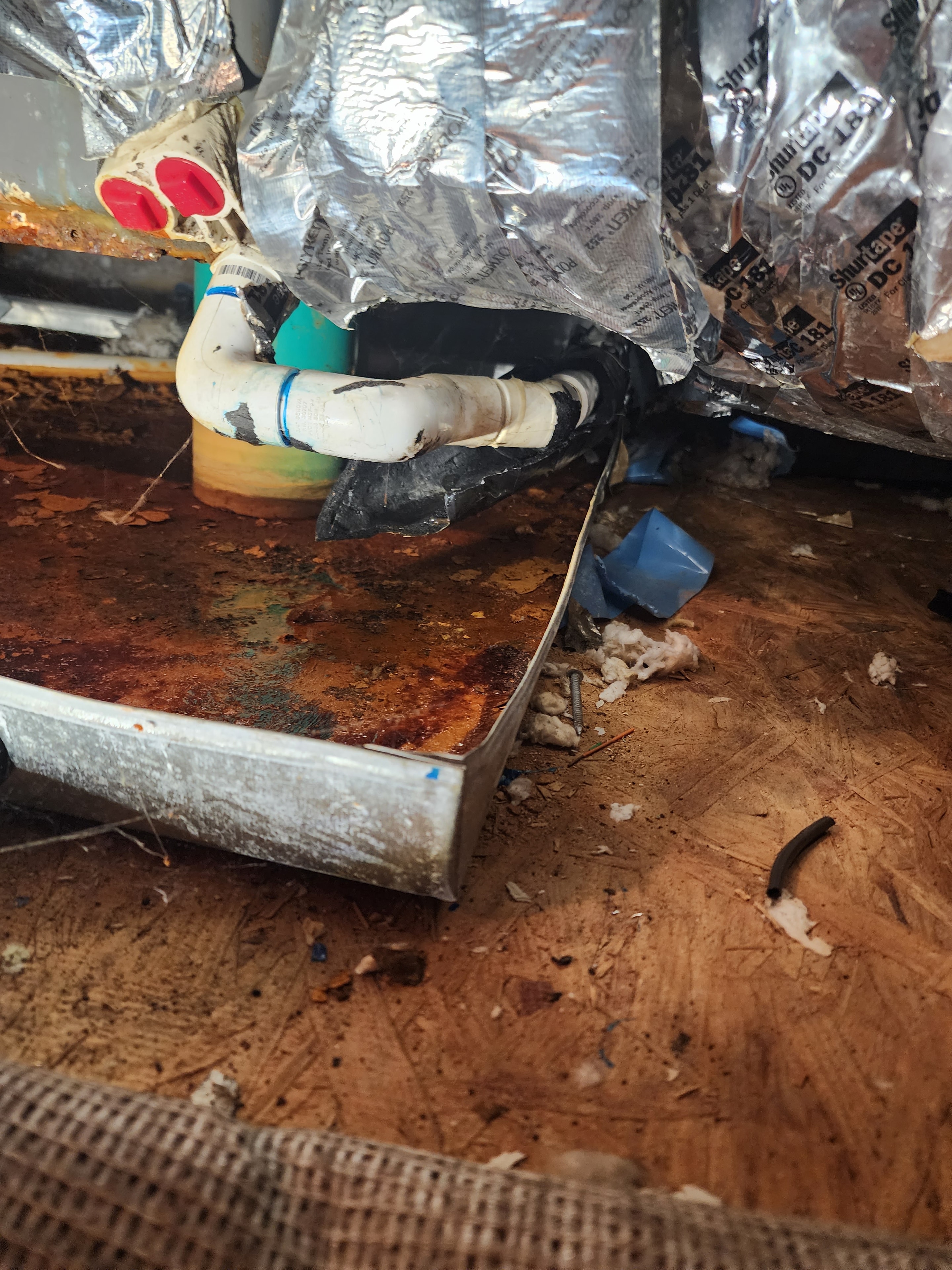 Rusted sheet metal plenum with deteriorated duct connections in crawlspace